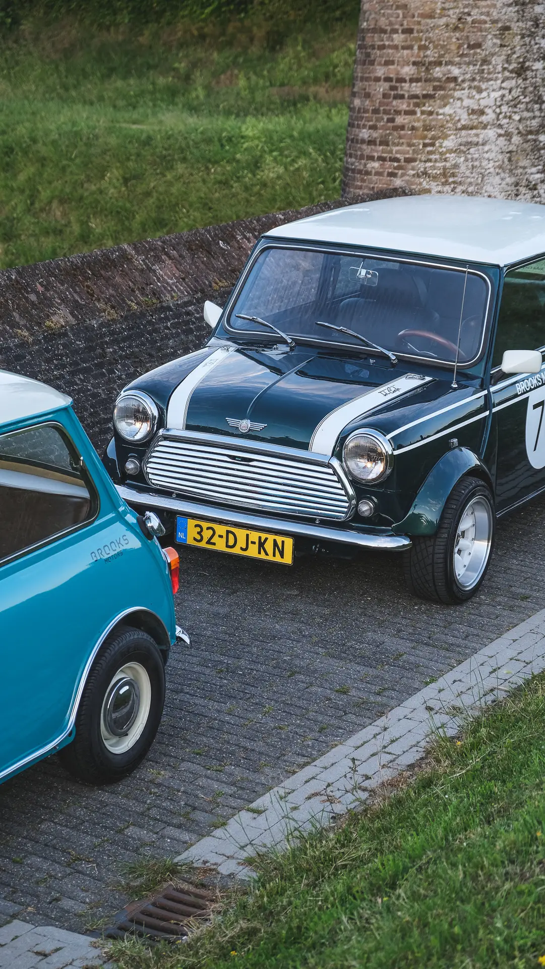 The Brooks motors Mini Cooper S standing between a wal and a light blue Mini Cooper S