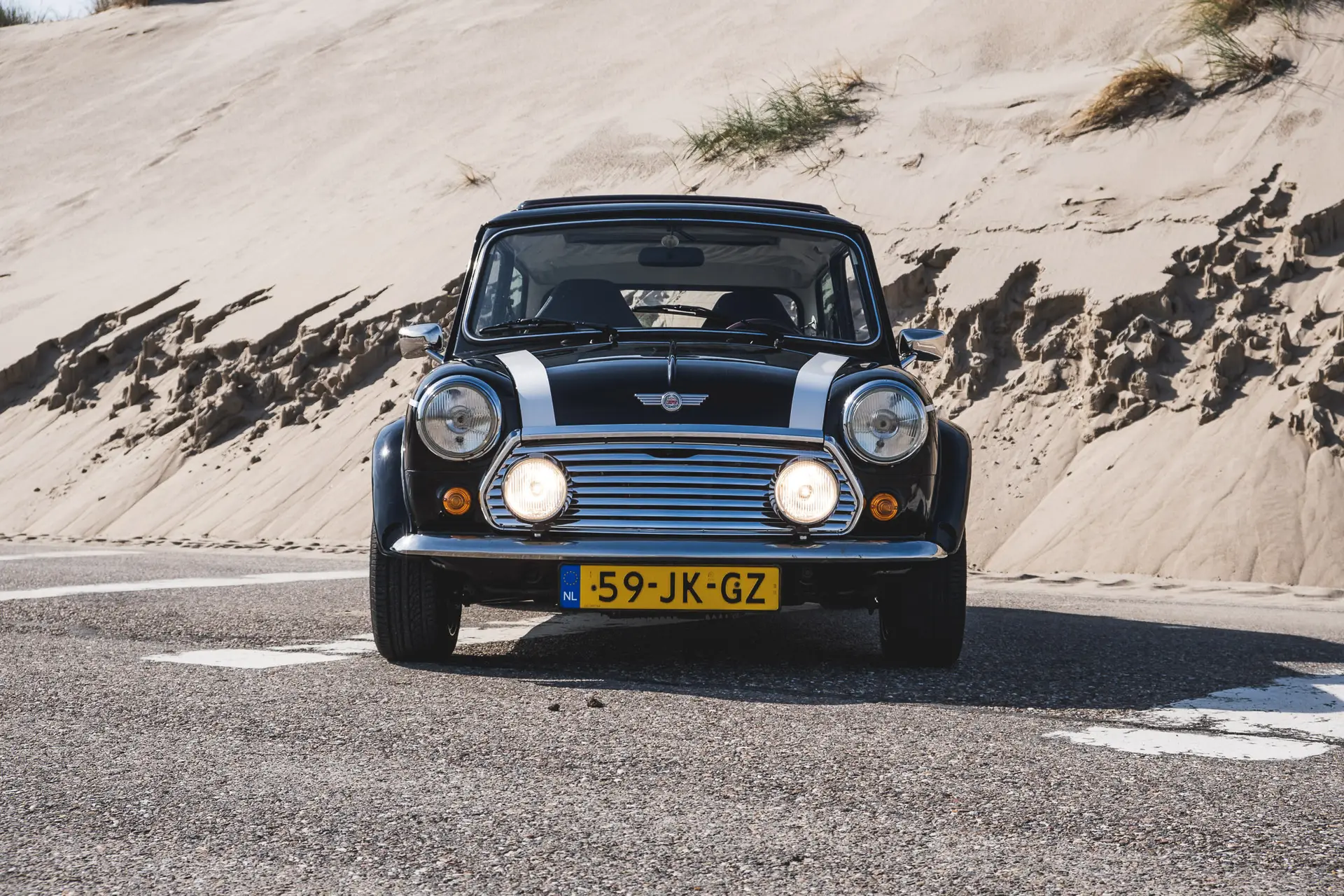 Recht voor de mini Oldtimer met koplampen aan op strand
